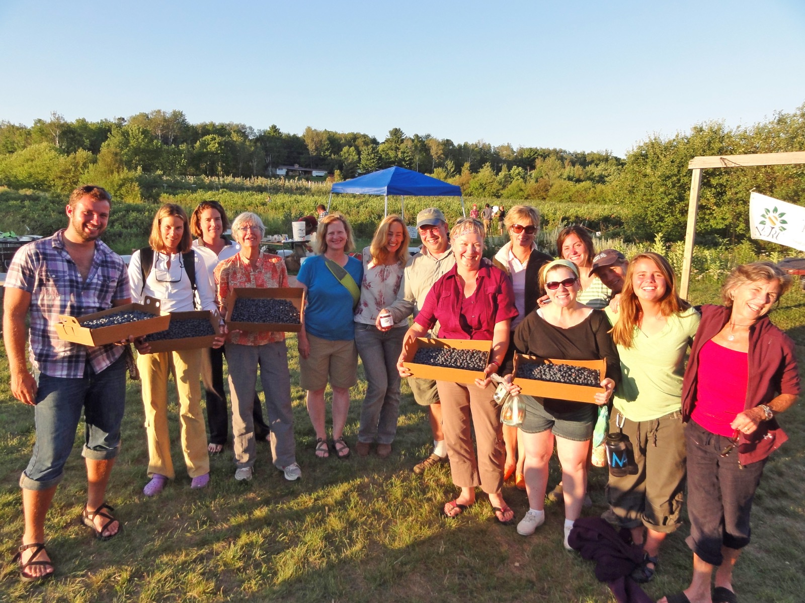 A group poses for the camera while holding many boxes of blueberries.