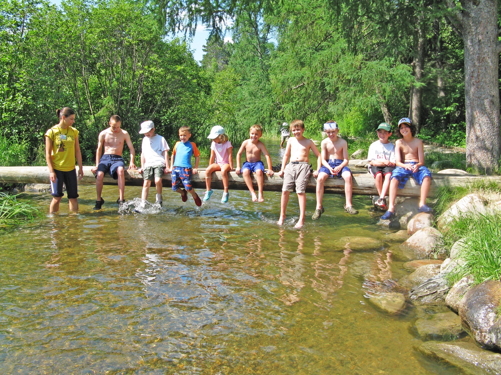 A group of kids sits on the wooden walkway that crosses the Mississippi River and dangle their toes in the water.